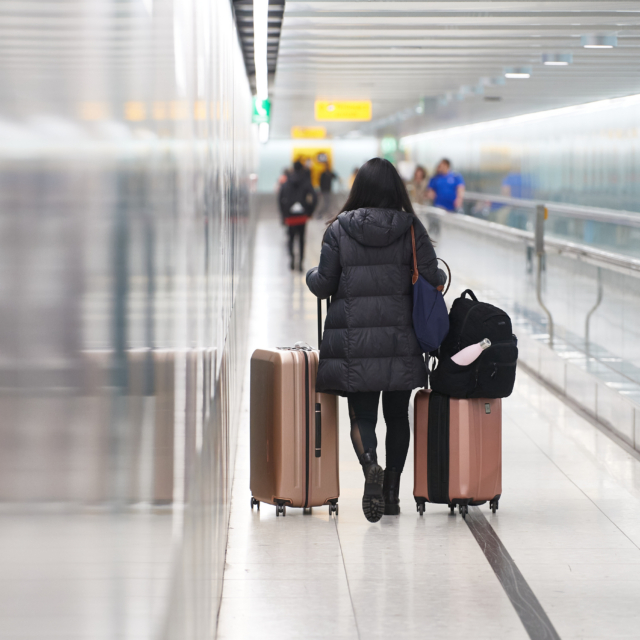 A passenger with luggage walks next to a travelator in a London Heathrow Airport Central Terminal Area.