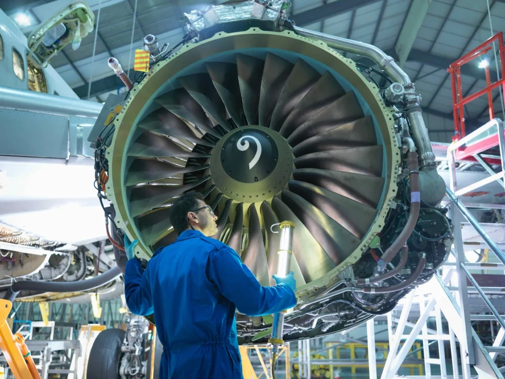 A worker at a maintenance repair and overhaul shop inspects an engine