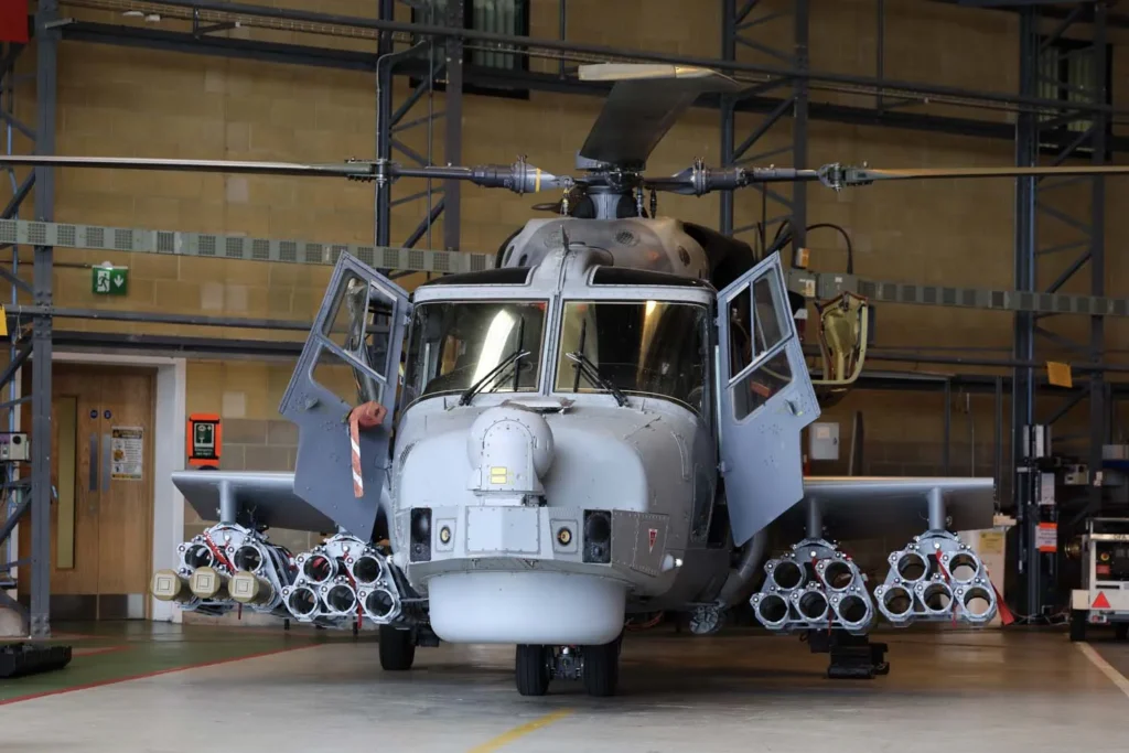 Royal Navy Wildcat helicopter fitted with additional sensors inside a hangar.