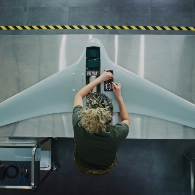 Woman in Camouflage Uniform Working installing batteries on Next Generation Drone.
