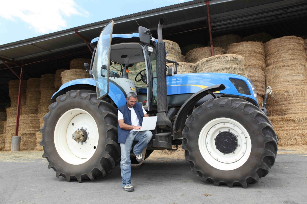 Farmer with his tractor using a laptop for WiFi