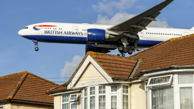 London, England - November 2018: British Airways Boeing 777 jet (registration G-VIIJ) flying low over houses to land at London Heathrow Airport.