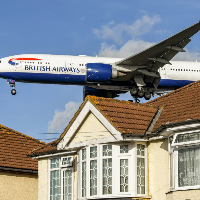 London, England - November 2018: British Airways Boeing 777 jet (registration G-VIIJ) flying low over houses to land at London Heathrow Airport.