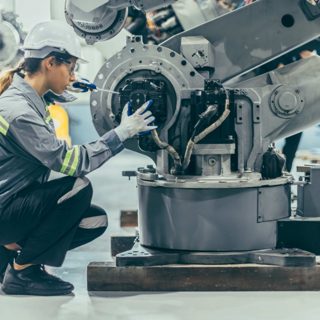 Engineer robotic mechanic women technician working in advance robotic industry plant work assembly robot arm repair fix maintenance or service large machine by hand skill