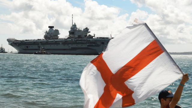 A youngster waves the Flag of St George as HMS Prince of Wales leaves Portsmouth in 2025