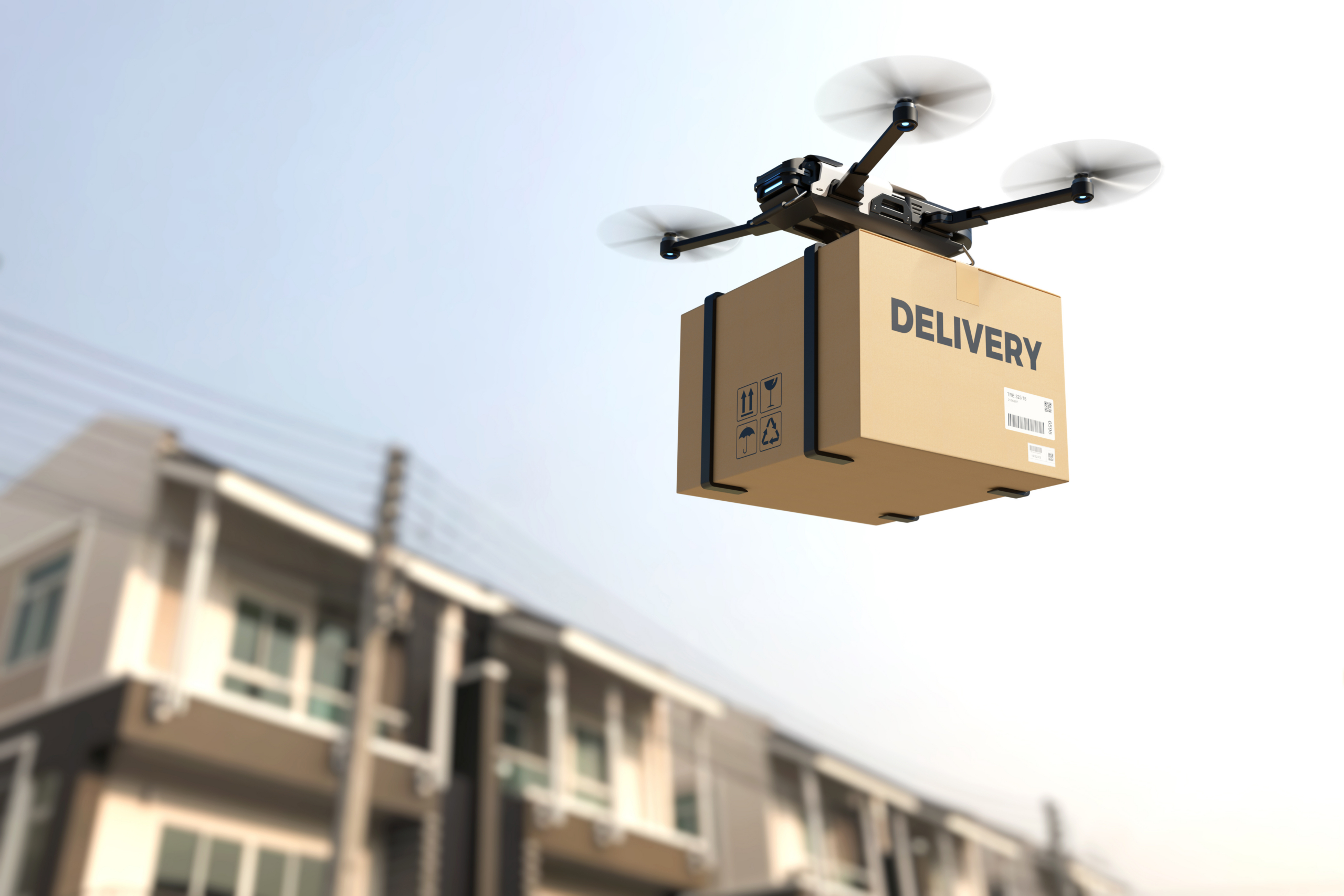 A drone flies with a package on delivery past residential houses.