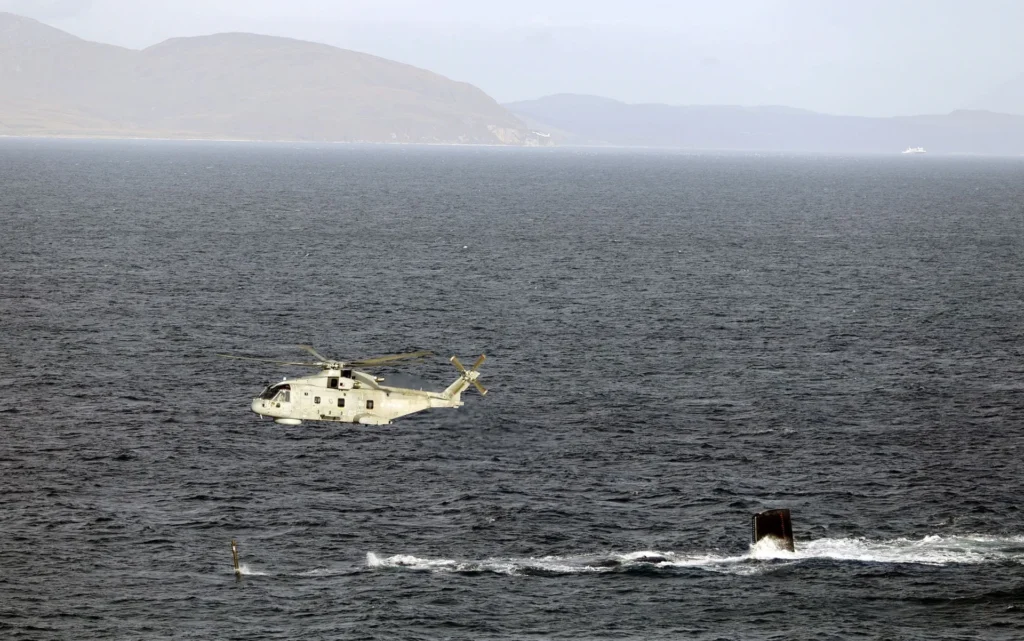 A Merlin HM2 passes over HMS Agamemnon (S124) as the Royal Navy's latest Astute-class nuclear attack submarine conducted sea trials in the Irish Sea during Operation Iceblast. Image: MOD Crown Copyright/Royal Navy